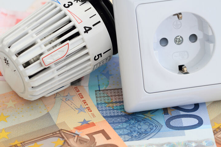 Thermostat und Steckdose liegen auf Geldscheinen