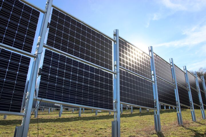 Foto von einer Reihe an senkrecht aufgestellten Solarpanels auf einer Wiese